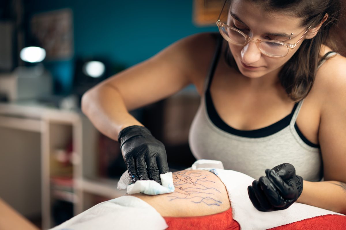 female tattoo artist wiping down fresh tattoo concept: tattoo aftercare
